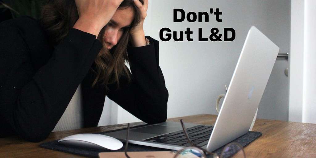 A woman hunched over her laptop with hands on her temples angry with text overlay "don't gut L&D."